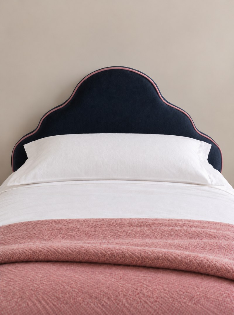 Finished scalloped navy headboard with blush piping, white bed linen and a blush throw