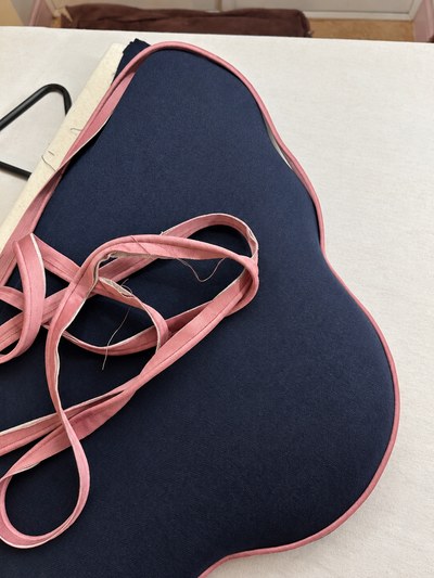 Scalloped navy headboard being made in the workroom, with loose blush piping ready to finish