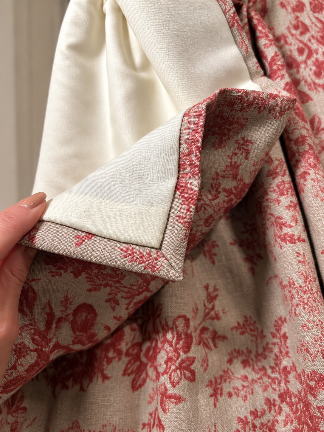 Cream curtain lining and a neatly finished hem on red floral fabric