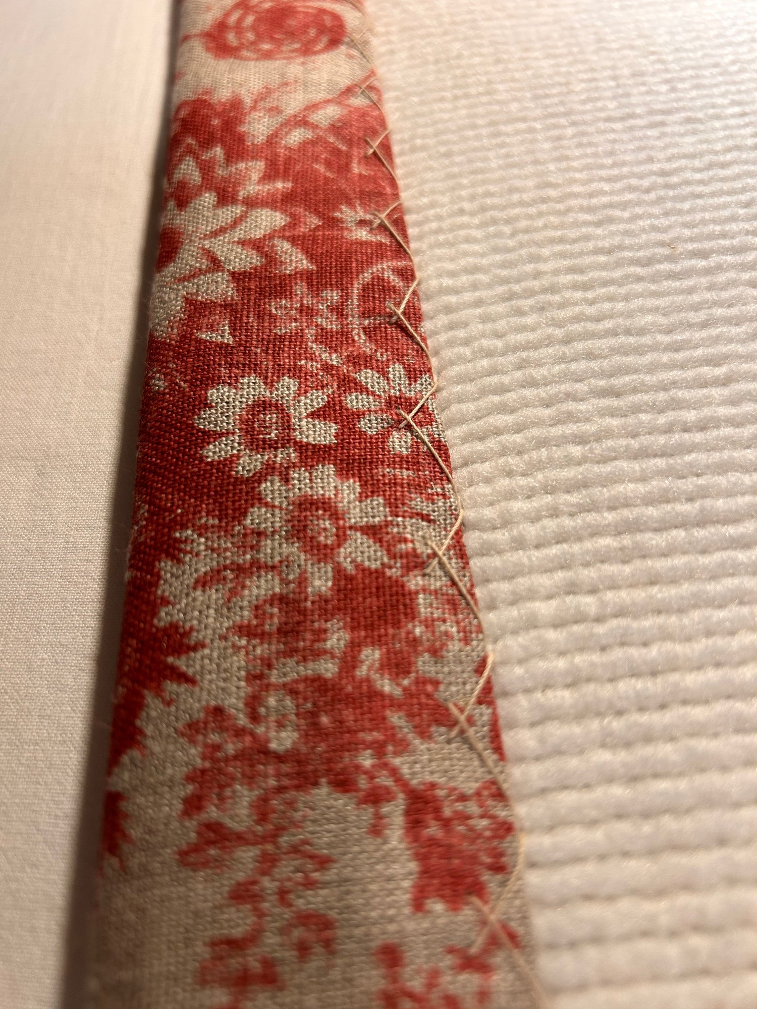 Hand stitching on red floral fabric with cream lining and soft interlining