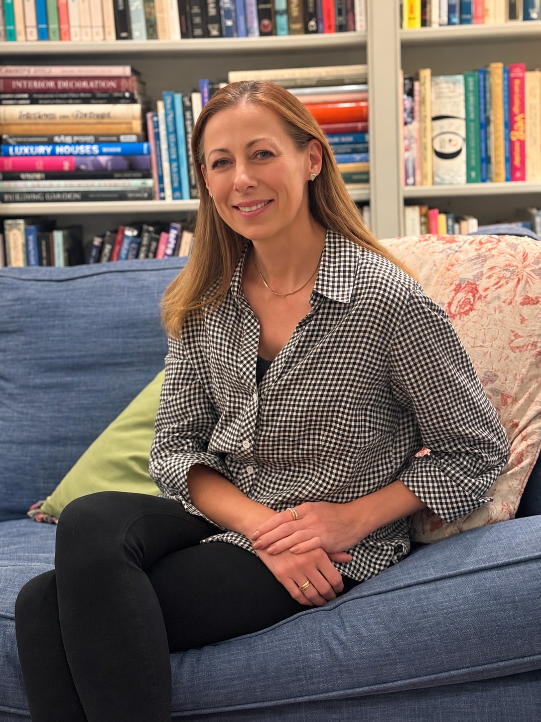 Roxanne, the maker behind Cloth & Elm, seated on a blue sofa in front of bookshelves